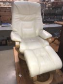 A reclining cream leather armchair with matching footstool