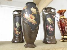 A pair of Bretby bird decorated vases and one other.