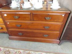 A 2 over 2 mahogany chest of drawers with protective glass top.