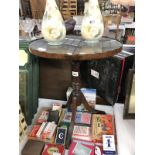 A dark wood stained oval tripod table with glass top