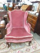 A pink upholstered wing arm chair.