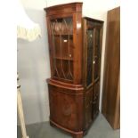 A dark wood stained corner cupboard with bow front astragal glazed door