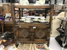 A dark oak tea trolley with cupboard underneath