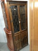 A country oak corner cupboard with leaded glass doors