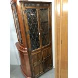 A country oak corner cupboard with leaded glass doors