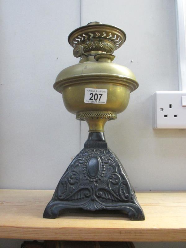 A Victorian oil lamp with brass font and cast iron base
