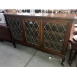 A dark oak 3 door display cabinet with leaded glass panels