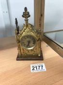 An early 20th century Gothic style small brass mantle clock