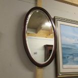 An oval mahogany inlaid wall mirror.