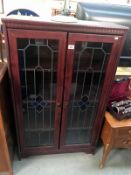 A mahogany effect display cabinet with painted glass doors
