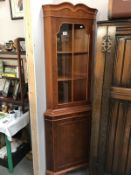 A dark wood stained corner cupboard with astragal glazed door