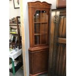 A dark wood stained corner cupboard with astragal glazed door