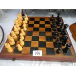 A cased wooden chess set with folding board