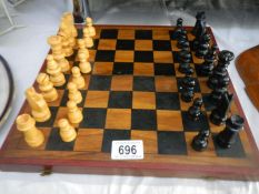 A cased wooden chess set with folding board