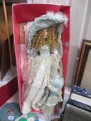 A tall porcelain doll in vintage dress