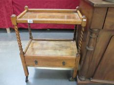 A two tier wooden trolley with drawer and barley twist sides