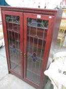 A glazed cabinet with leaded style doors