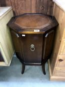 A dark wood stained octagonal drinks cabinet with leather inset top