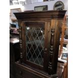 A dark stained pine corner cupboard with leaded glass door