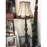 A turned dark wood stained standard lamp with shade.