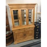 A light oak display cabinet on cupboard base.