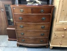 A mahogany veneered bow front chest of drawers with brass handles.