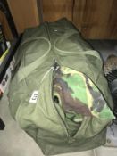 An army kit bag with an number of camouflage jackets and trousers.