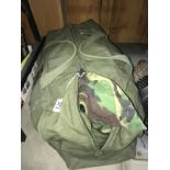 An army kit bag with an number of camouflage jackets and trousers.