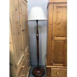 A dark wood stained standard lamp with shade.