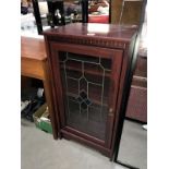 A dark wood stained display cabinet with decorative door
