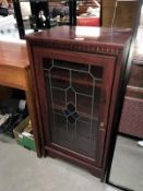 A dark wood stained display cabinet with decorative door