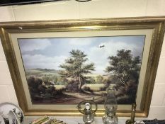 A large gilt framed print of countryside.