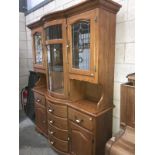 An ornate oak bow front dresser with leaded glass doors.