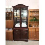 A dark wood stained glazed display cabinet on cupboard/drawer base