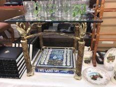 An ornate glass topped coffee table with swan rests.