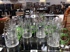 A large quantity of drinking glasses and a jug with green handles.