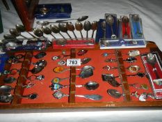 A quantity of souvenir spoons on a rack and other spoons