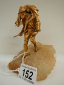 A small gilded figure of a mountain goat farmer standing on a rock, 5.5" tall.