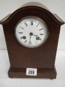 An oak mantel clock in working order complet with key and pendulum (chip on face)