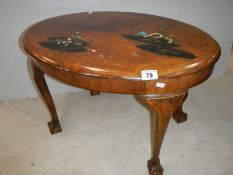 A small oval mahogany table with lacquered pictures, on ball and claw feet, in fair condition.