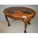 A small oval mahogany table with lacquered pictures, on ball and claw feet, in fair condition.