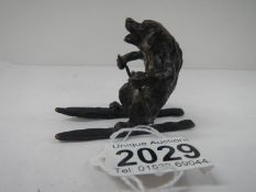 An early painted bronze of a dog on skis 2 inches high