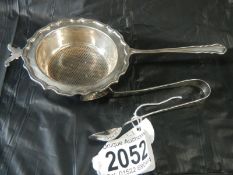 A silver strainer and silver sugar nips