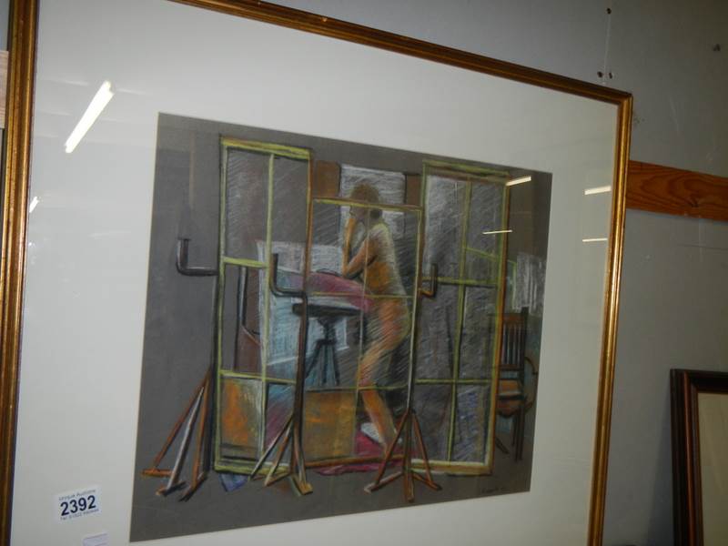 A framed and glazed S Barnes 1960's pastel drawing of a female nude in a studio behind a screen,
