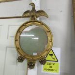 A gilt framed circular mirror surmounted eagle.