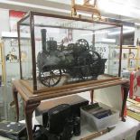 A handbuilt clockwork traction engine in custom built case on stand. Cabinet is 78cm long x 46.