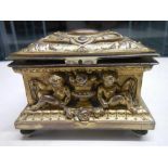 A 19th century gilded bronze casket with frolicking cherubs beside urns, silk lines.