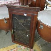 A glazed mahogany wall mounting corner cabinet.