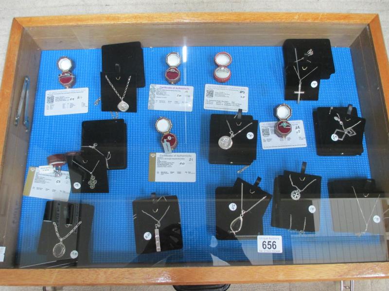 A display case containing 6 silver rings, all with certificates, and 10 silver pendants.