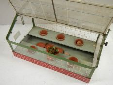 An old model tin green house with lift up roof, catch missing from one side of roof.